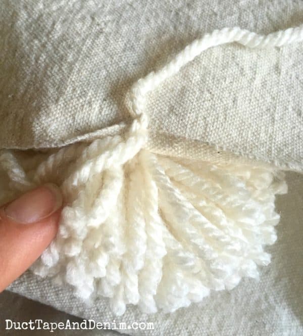 Tying pom poms to drop cloth throw blanket | DuctTapeAndDenim.com