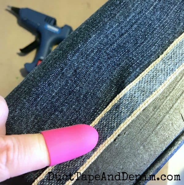 Hot glue denim ribbon to cover upholstery staples | DuctTapeAndDenim.com
