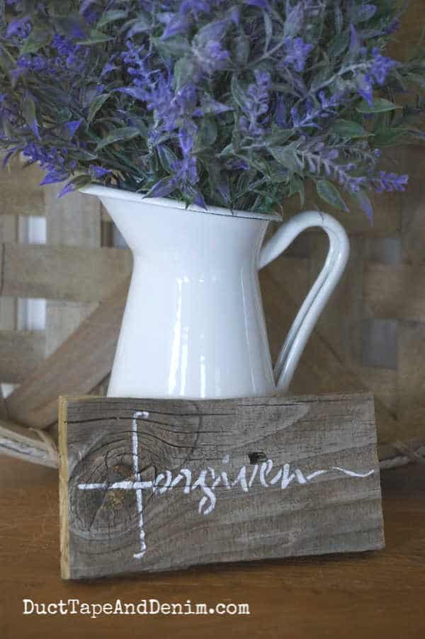 Forgiven cross sign with lavender blooms in white pitcher
